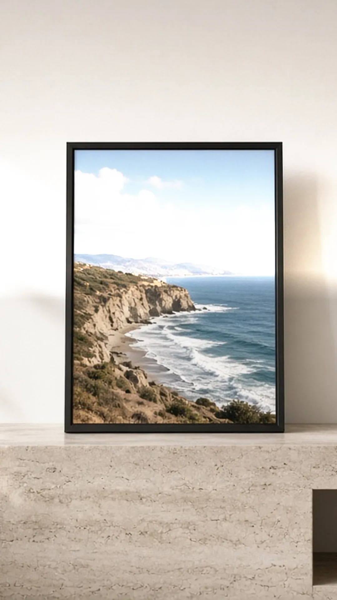 Digital frame showing a coastline photo on a travertine console